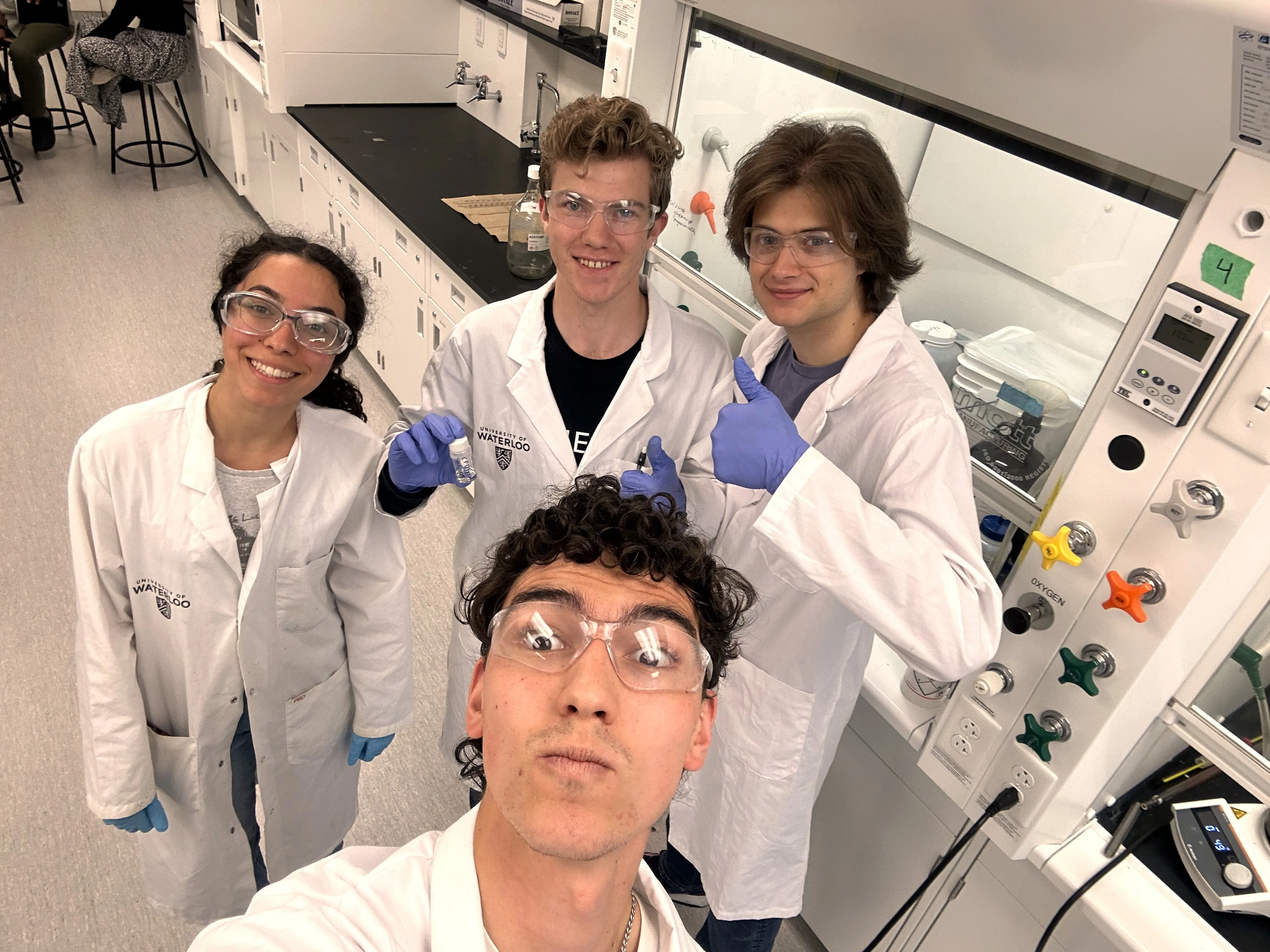 Selfie of 3 Formula Nano team members in a lab smiling at camera